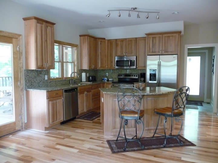 Kitchen with light wood cabinetry, granite countertops, stainless steel appliances, and a central island with seating.