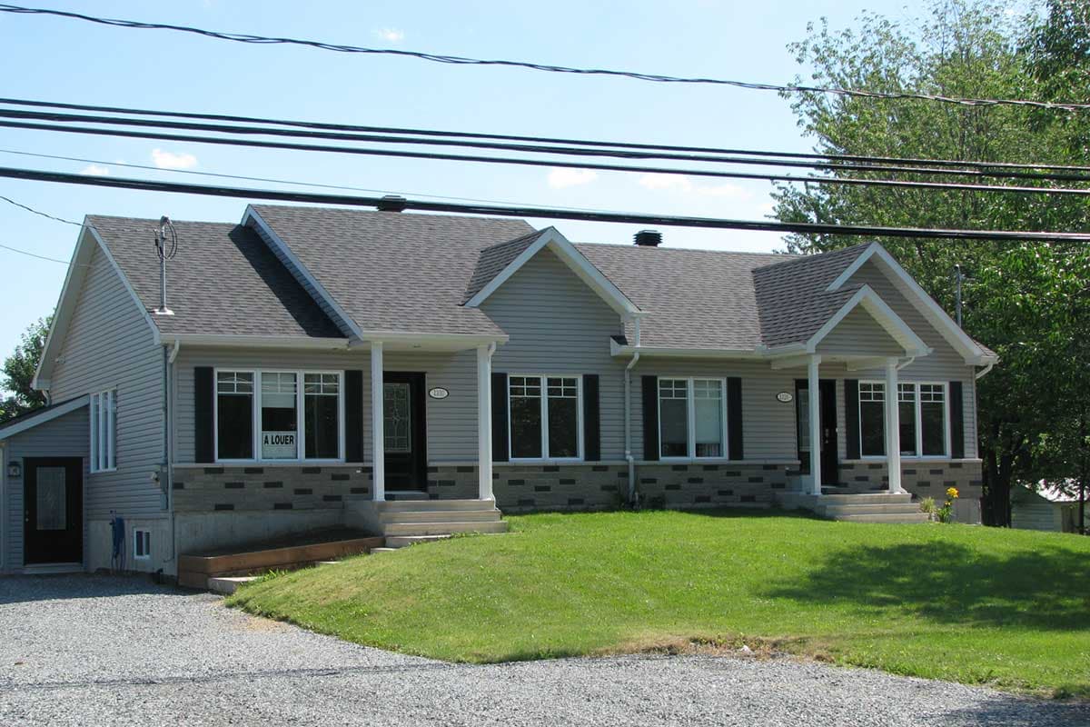 House plan exterior: One-story duplex with gabled roofs, vinyl siding, stone accents, and covered porches.