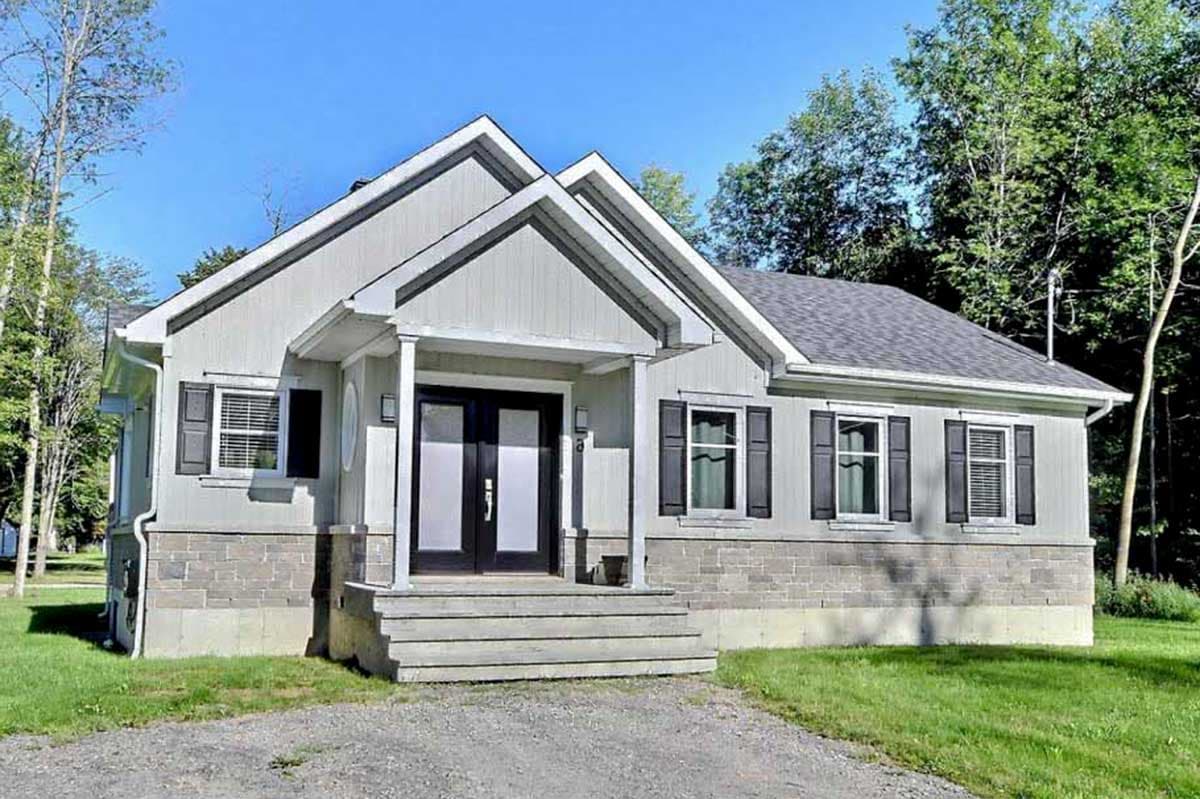 House plan exterior with gable roof, front porch, and shutters. Two-story structure with stone facade base and light siding.