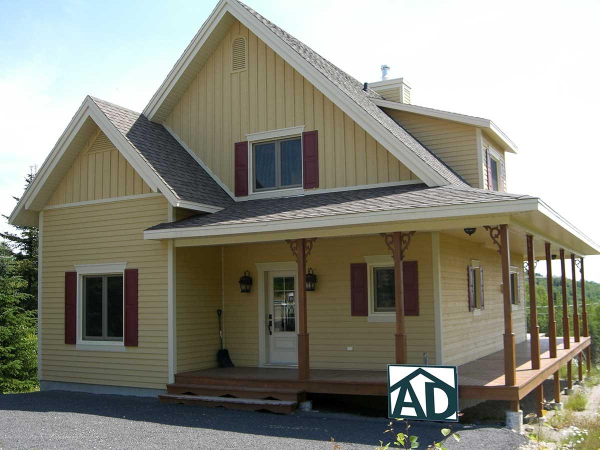 House plan exterior of a two-story home with a wraparound porch, gabled dormers, and vertical siding.