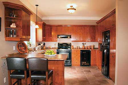 Kitchen with wood cabinetry, black appliances including a refrigerator, stove, and wine cooler, and a central island with bar stools.