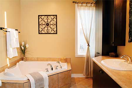 Bathroom with corner whirlpool tub, dual sinks, and dark wood vanity. Window with sheer curtains.
