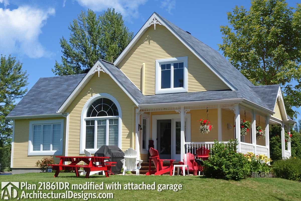 House plan exterior featuring a yellow facade, wrap-around porch with white railings, arched window, and gabled dormers.