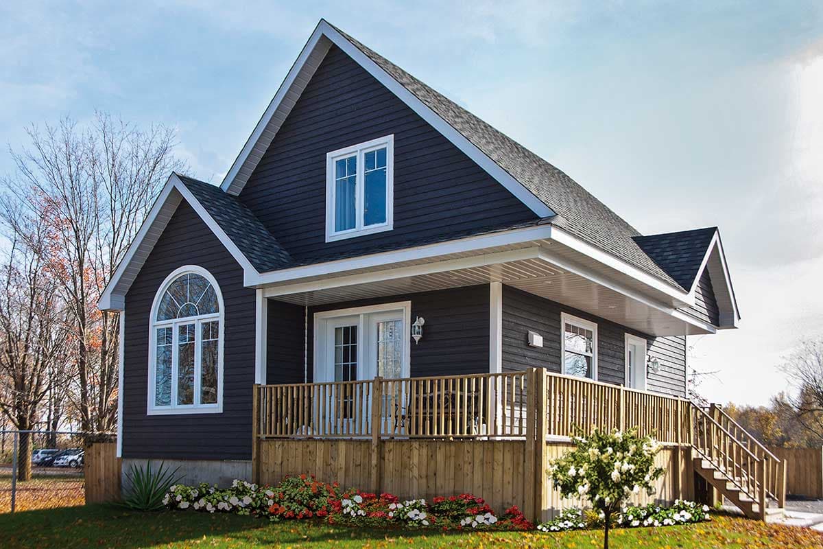 House plan exterior. Two-story home with a gabled roof, a covered porch with a railing, and a Palladian window. Dark siding.