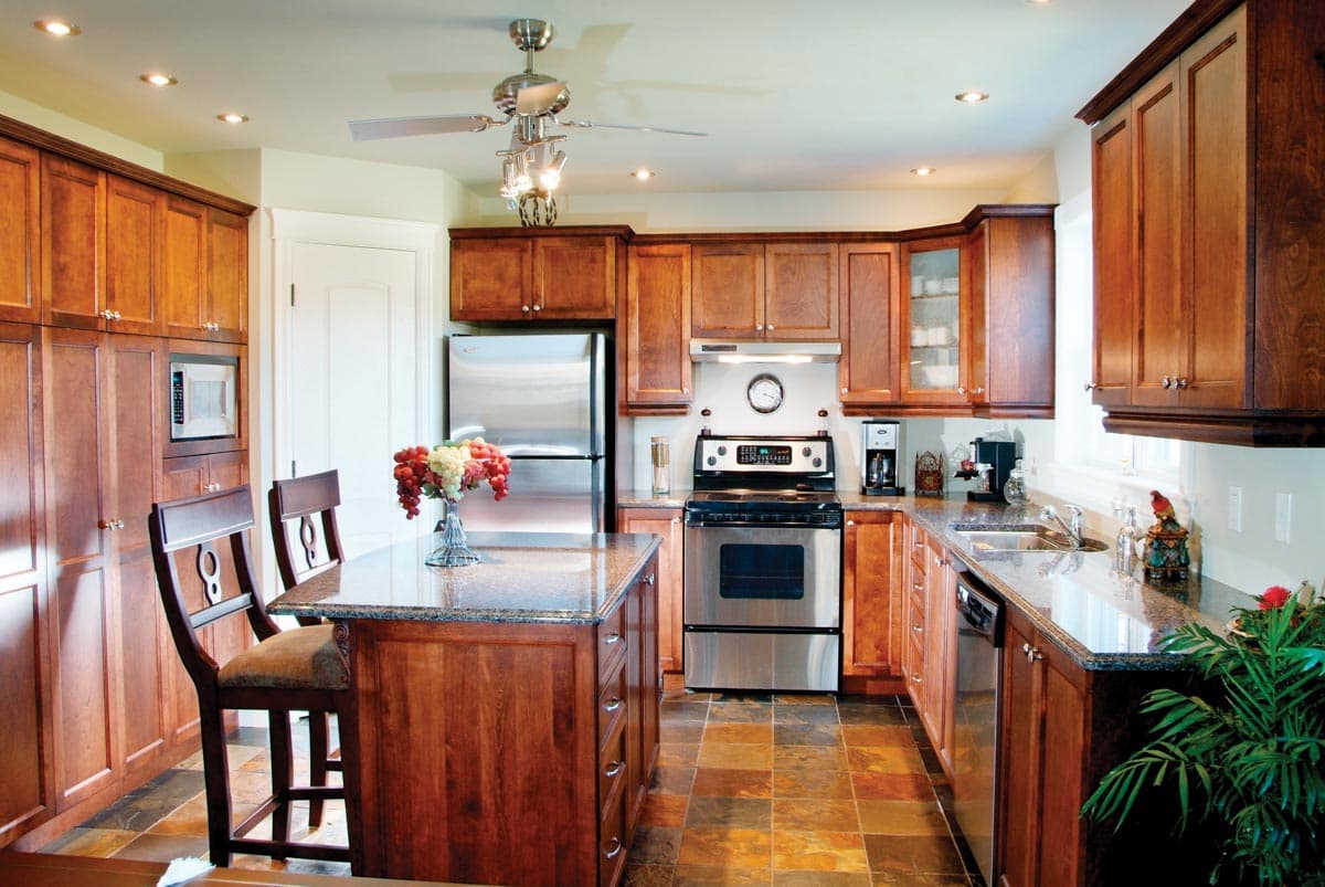 Kitchen with wood cabinetry, granite countertops, stainless steel appliances including a refrigerator, range, and dishwasher, and a center island.