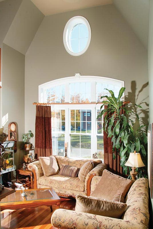 Interior view of living room with vaulted ceiling, large arched window, and oval dormer window.