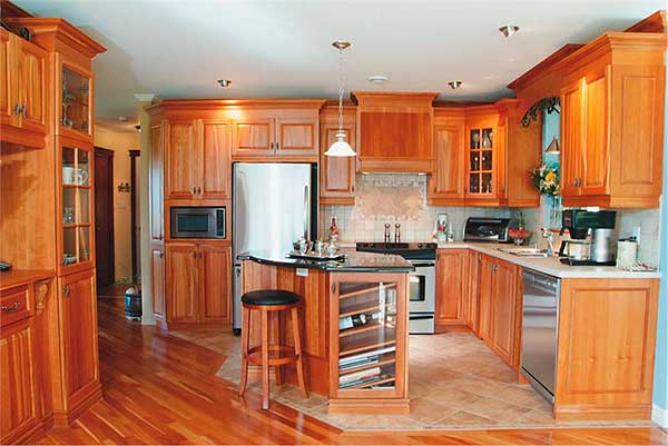 Kitchen with honey wood cabinetry, stainless steel appliances including refrigerator, microwave, stove, dishwasher and island with wine storage.