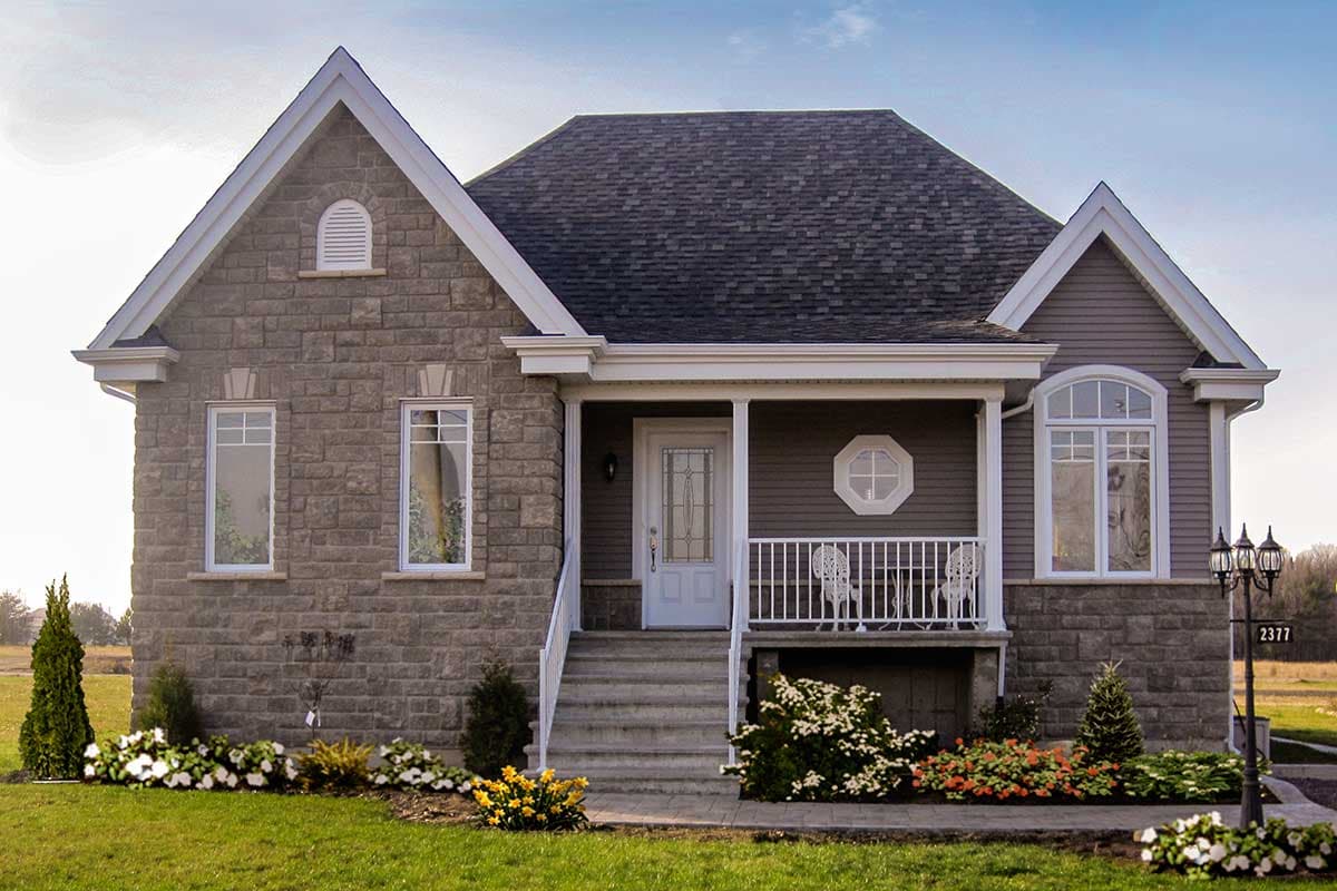 House plan exterior with stone facade, pitched roof, covered porch with railing, and arched window.