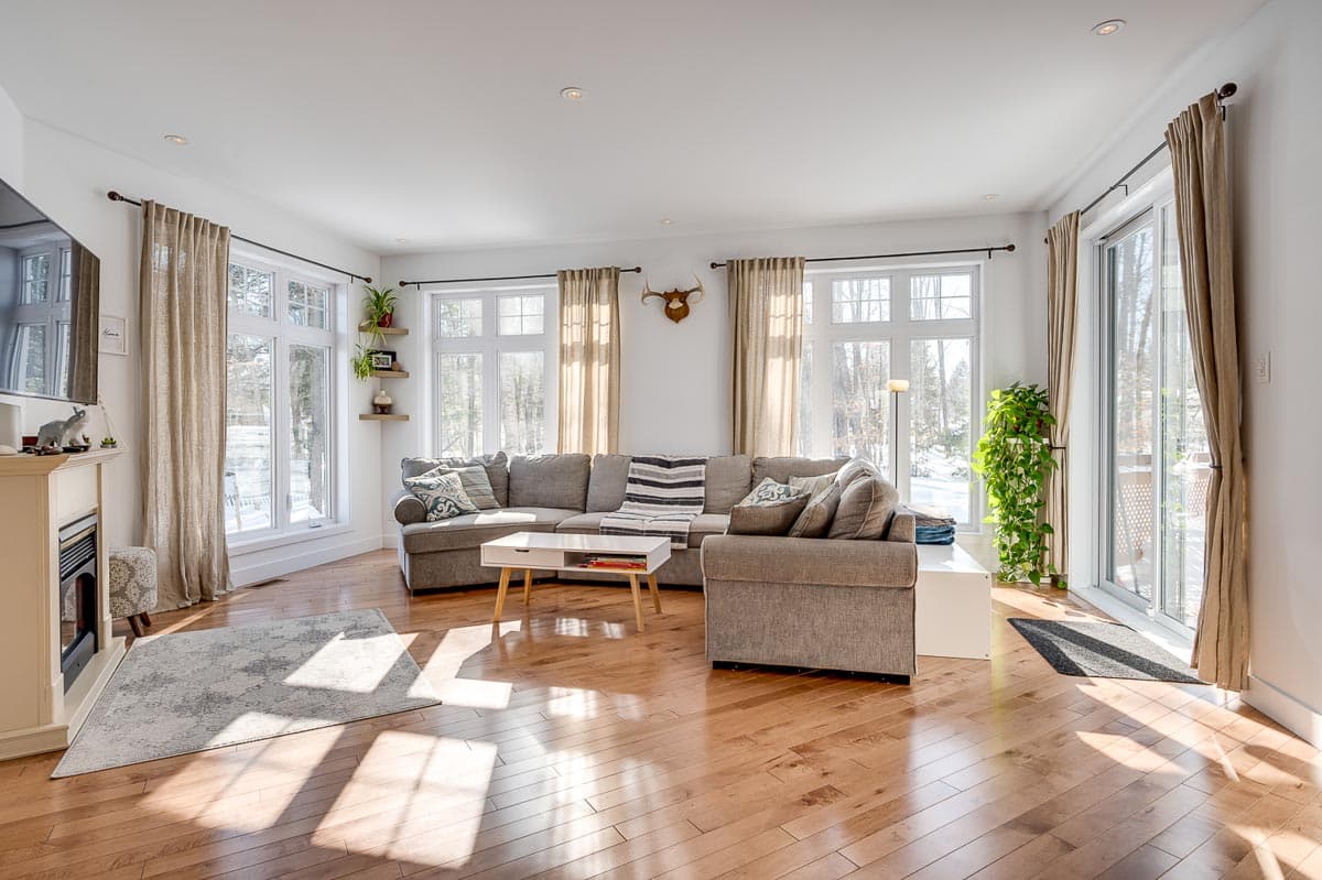 Living room with sectional sofa, fireplace, large windows, and sliding glass door.