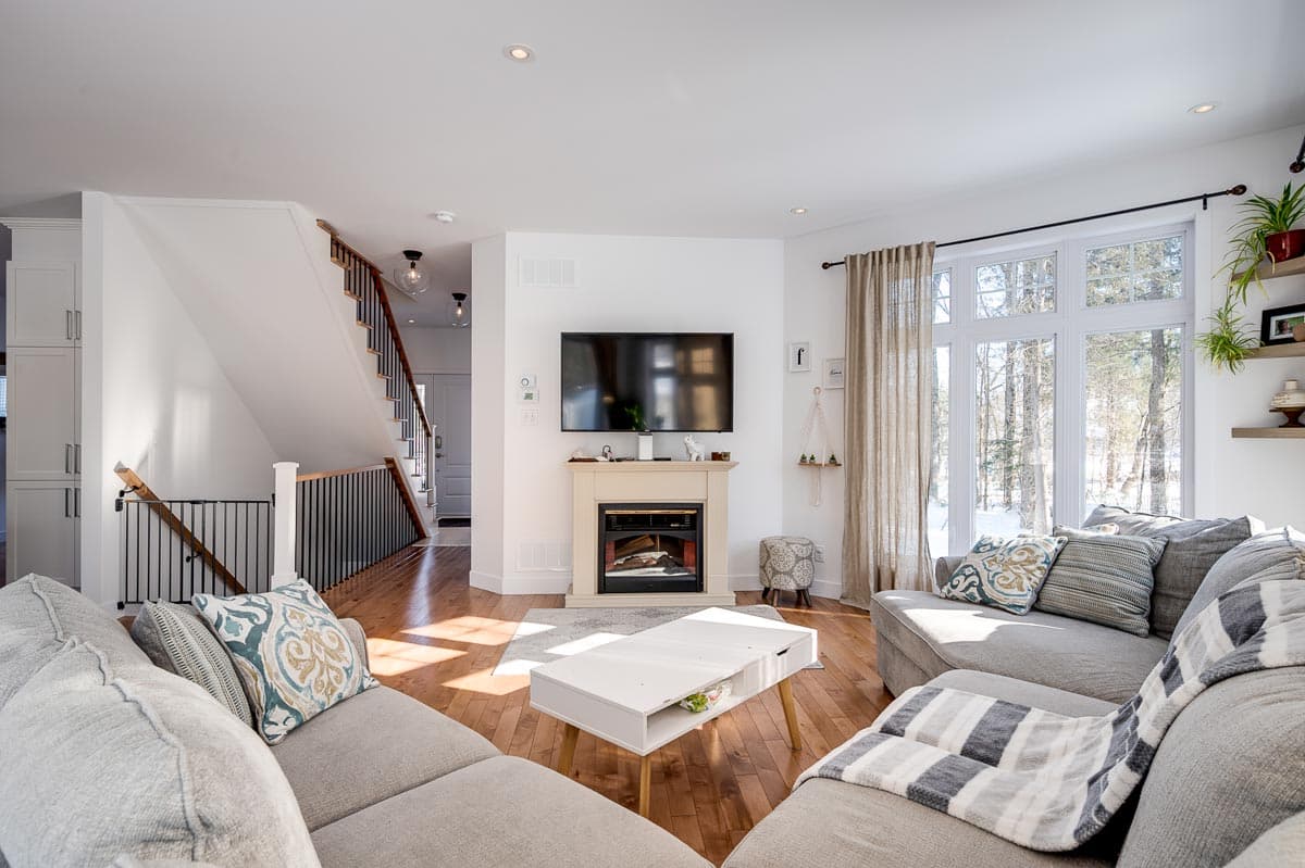Living room with fireplace, TV, sectional sofa, coffee table, and view of stairs leading to second floor.
