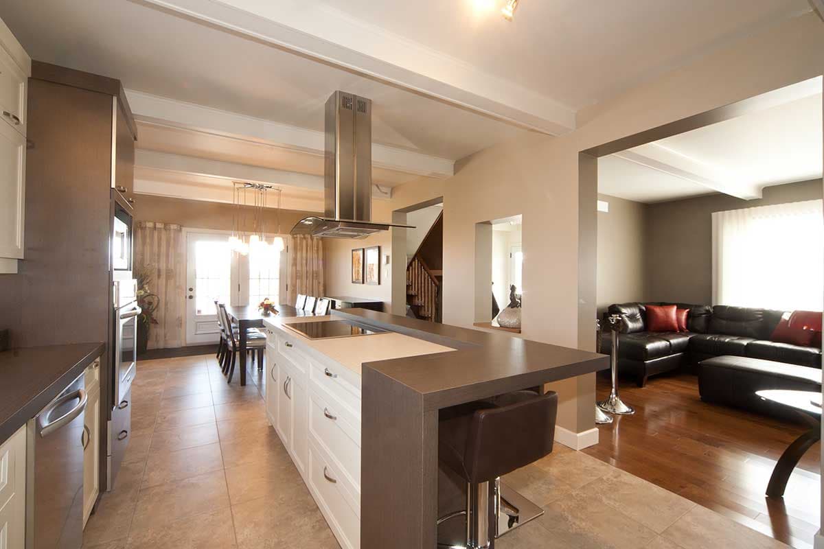 Open-concept kitchen with island, dining area, and living room featuring a sectional sofa and fireplace.