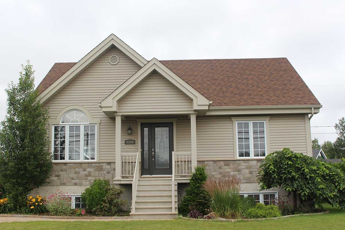 House plan exterior with tan siding, stone foundation, front porch with double entry doors, and arched window.