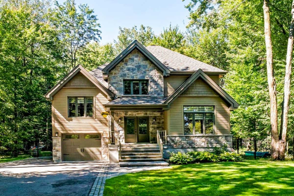 House plan exterior featuring a two-story Craftsman home with a stone facade, gabled roof, and attached garage with a carriage-style door.