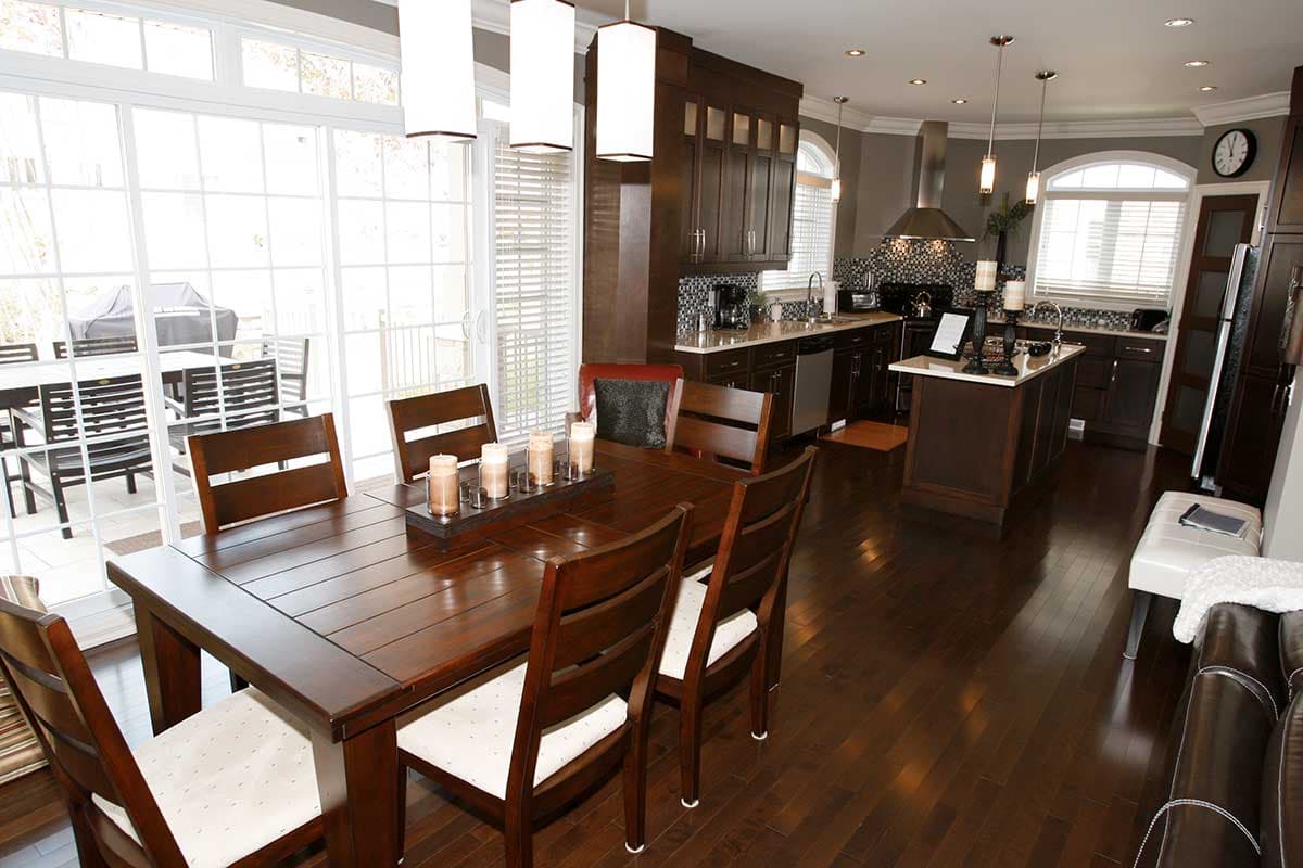 Open concept dining area and kitchen with dark wood cabinets, island, and large sliding glass doors.