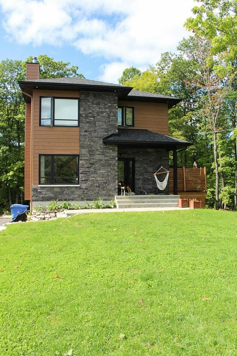 Two-story modern house plan exterior with wood siding, stone facade, dark roof, and covered entry.