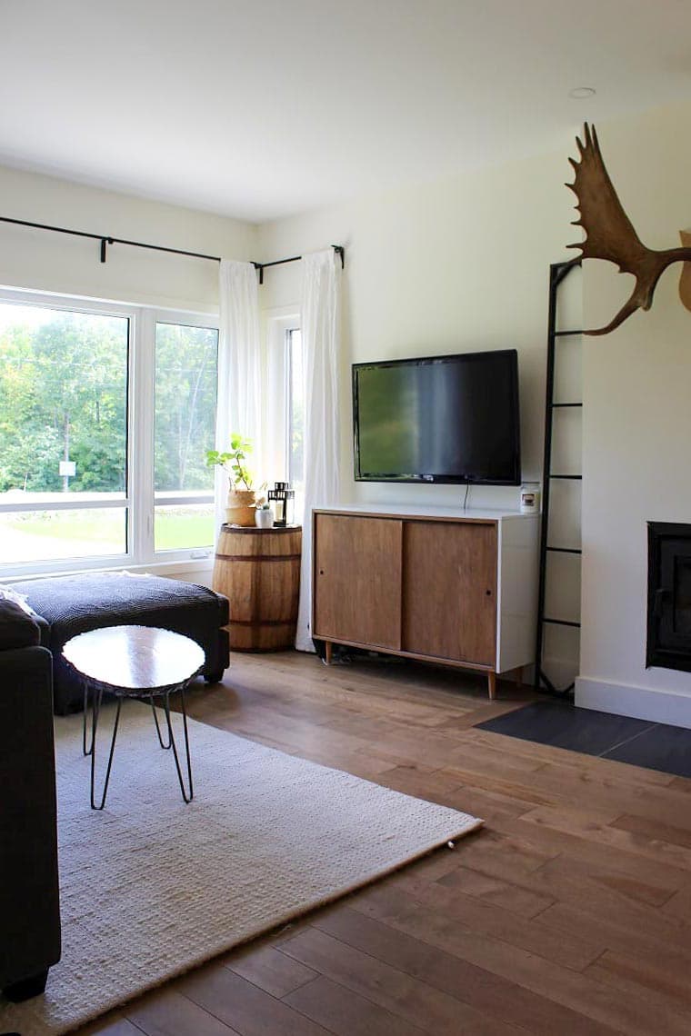 Living room with fireplace, large windows, wooden media console, and mounted television.