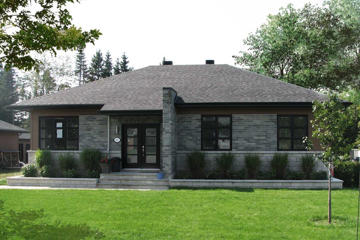 Ranch house plan exterior with stone and wood siding, gabled roof, central chimney, and double entry doors.