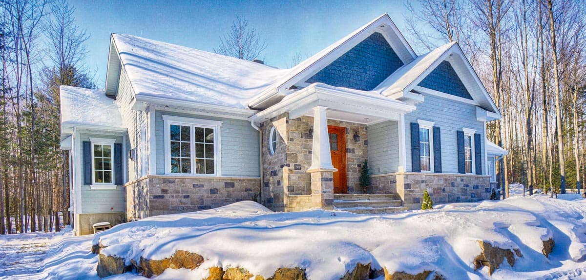 House plan exterior: one-story Modern Farmhouse with gabled dormers, stone skirting, covered porch with columns, and multi-pane windows.
