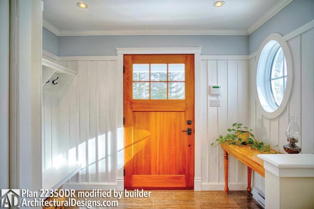 Entryway with wood door, bench, coat hooks, and oval window. Plan 2235DR.