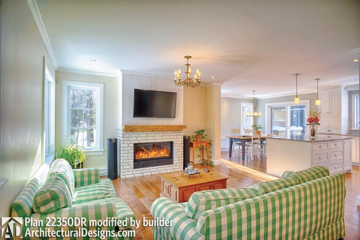 Open-concept living space with a white brick fireplace, entertainment center, kitchen island, and dining area.
