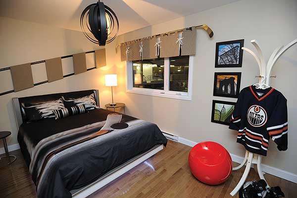 Bedroom with a hockey-themed duvet, metal wall art, window with valance, framed city photos, and a coat rack with a jersey.