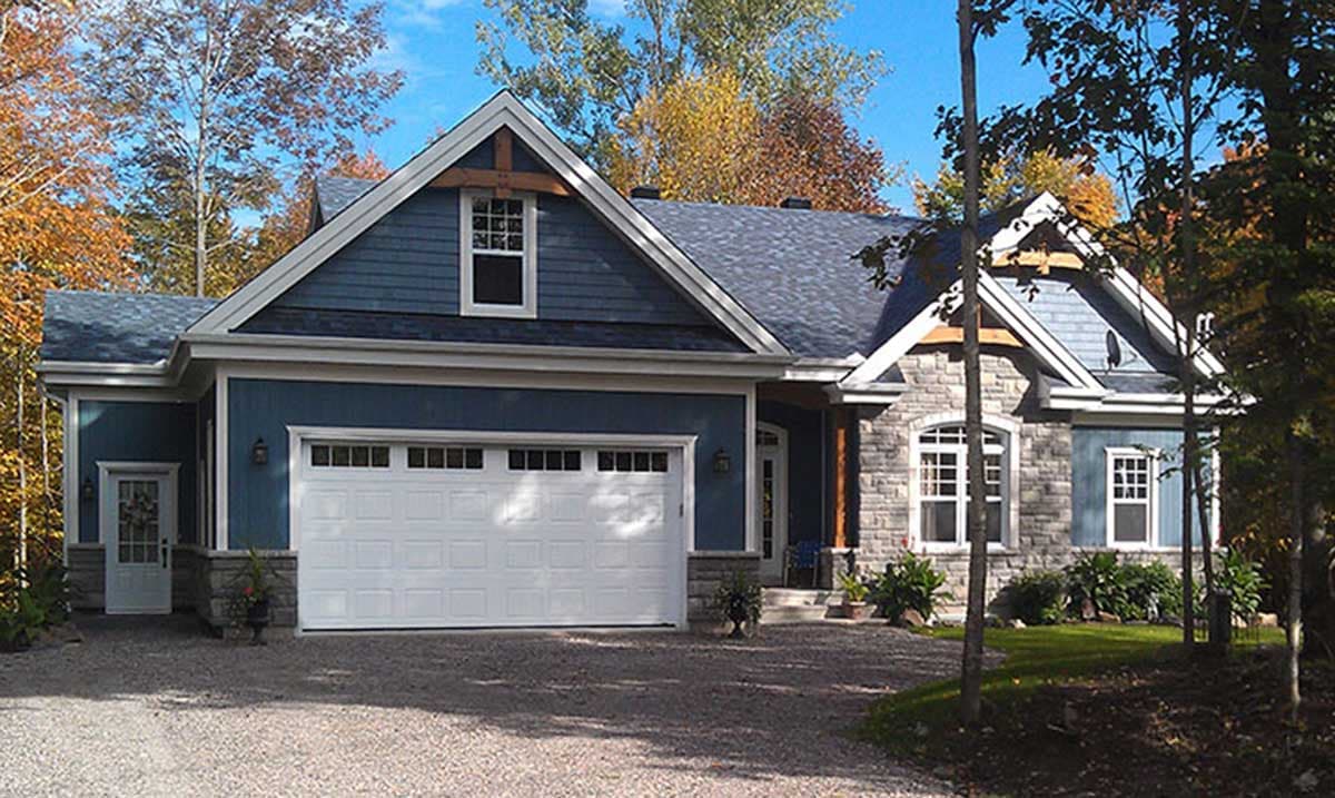 House plan exterior with stone and blue siding, prominent gable with exposed wood beams, and large garage door.