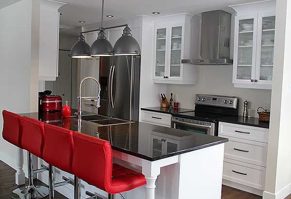 Modern kitchen featuring a large island with bar seating, stainless steel appliances, and white cabinetry with glass fronts.