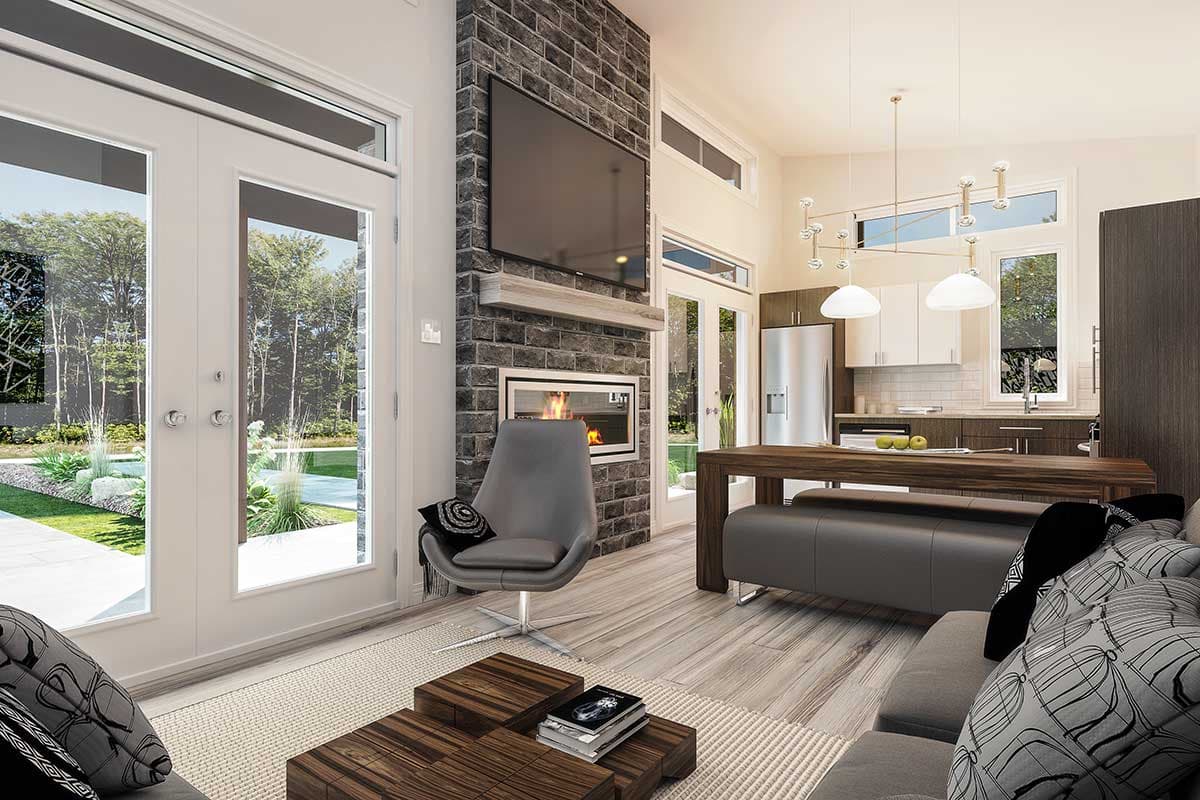 A modern living room with large windows, a brick fireplace, and a kitchen visible in the background. A gray chair sits nearby the fireplace.