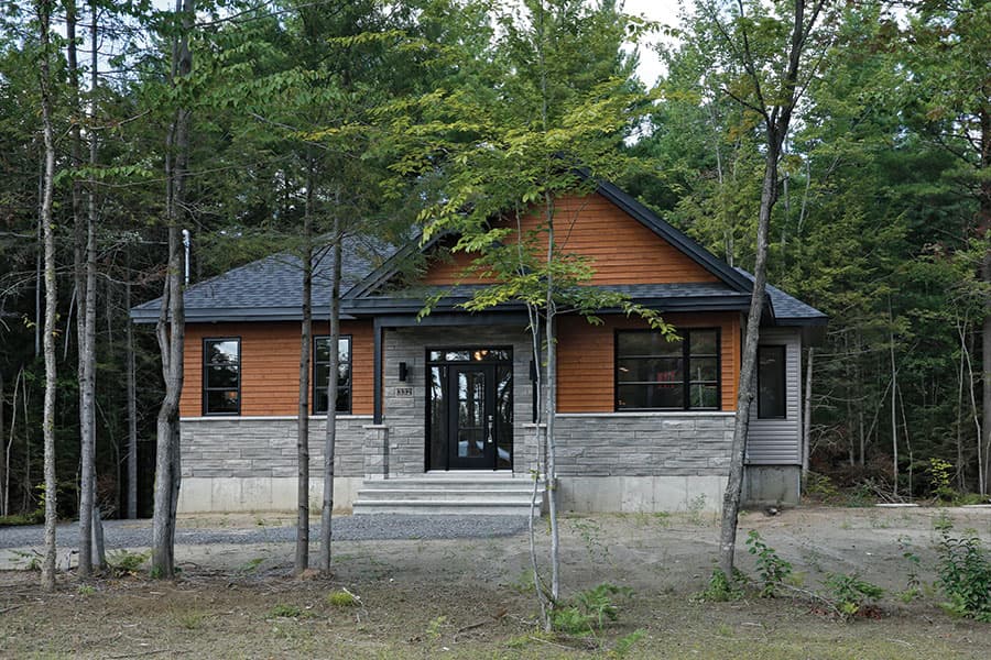 Modern house plan exterior with stone and wood siding, a covered entryway, and dark-framed windows.