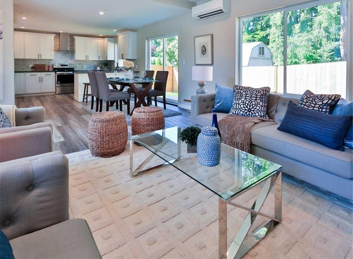 Interior rendering of an open concept living, dining, and kitchen area with a sectional sofa, dining table, and kitchen island.