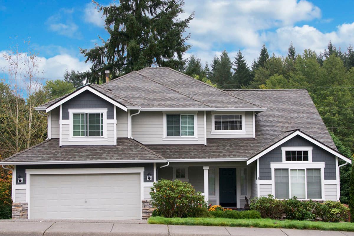 House plan exterior: Two-story home with attached garage, prominent gables, stone accents, and a covered front porch.