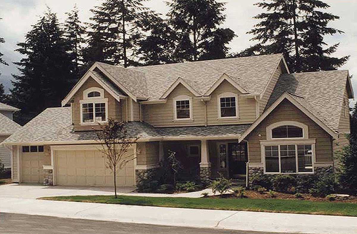 Two-story house plan exterior with a gable roof, dormers, arched windows, stone accents, and a three-car garage.