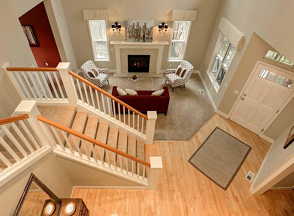 Interior view of house foyer and living room with a fireplace, staircase, and front door.
