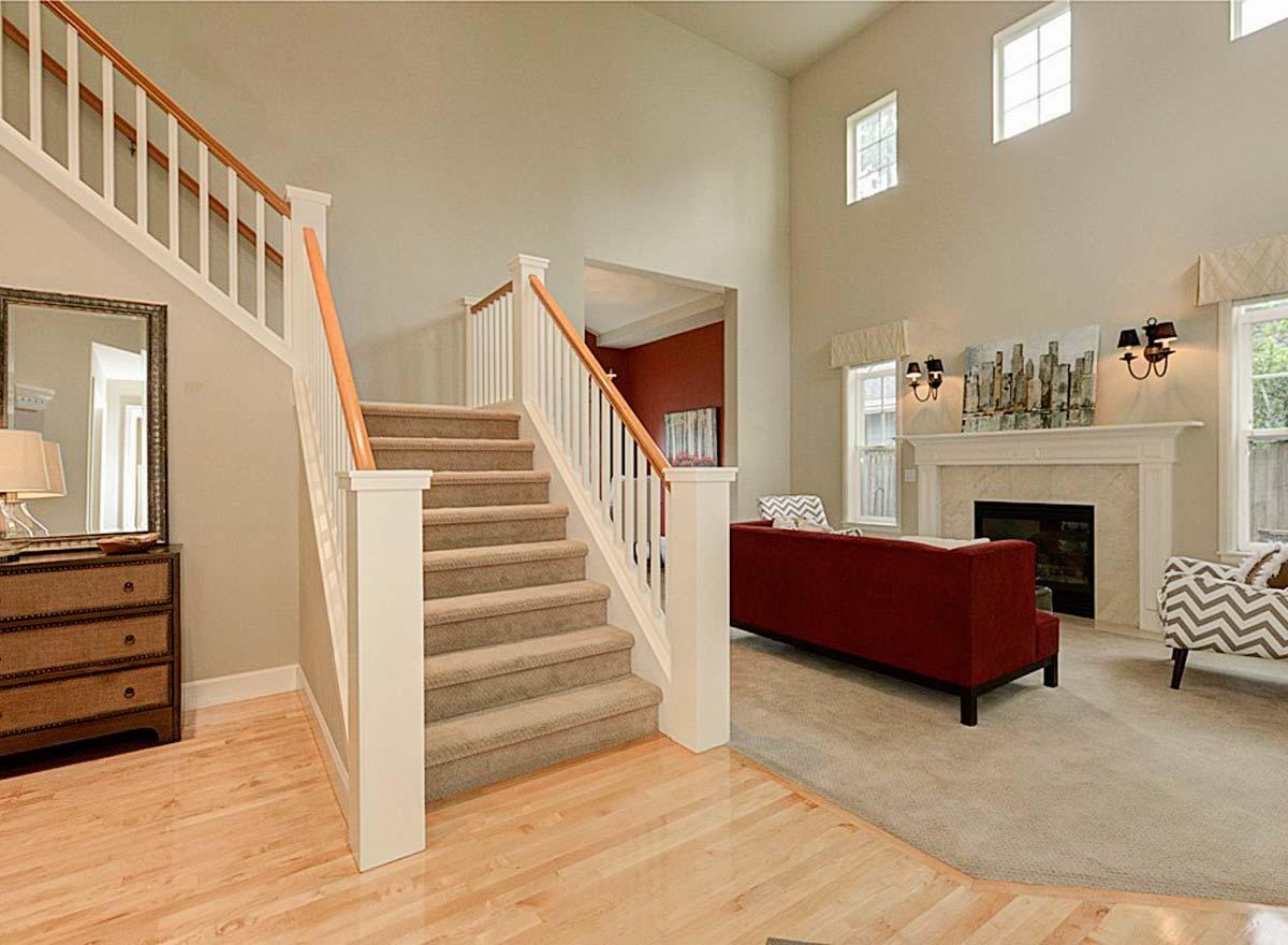 Interior view of house with carpeted staircase, vaulted ceiling, fireplace, and seating area.