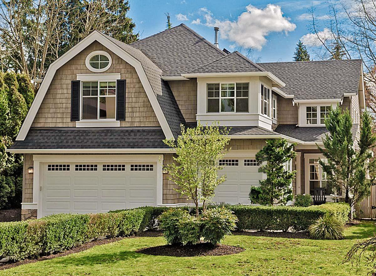 House plan exterior with two stories. Features include a gambrel roof, dormers, and a two-car garage. Shingle siding is visible.