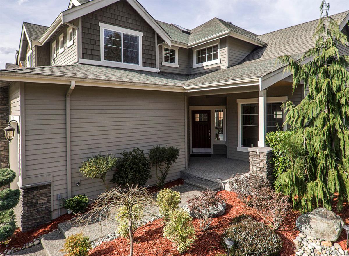 House plan exterior: Two-story home with vinyl siding, stone accents, gabled dormers, and covered entry porch.