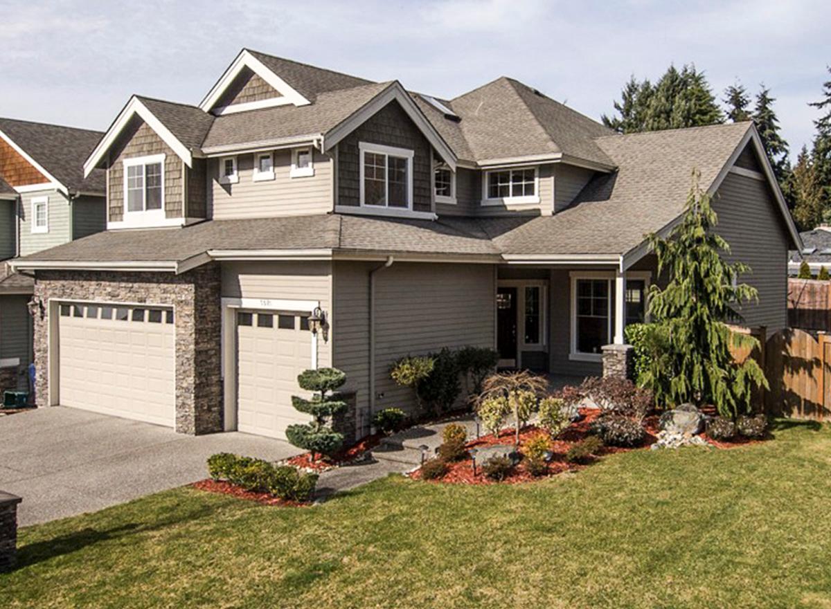 House plan exterior with stone accents, gabled dormers, multiple rooflines, and a three-car garage.