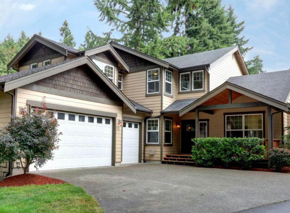 House plan exterior: Two-story home with a three-car garage, dormers, shake siding, and a covered front porch.