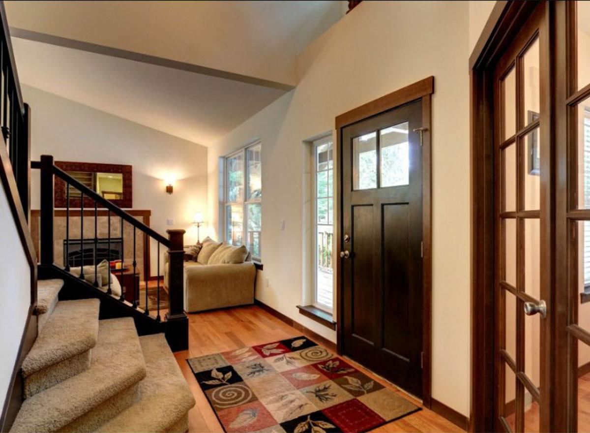 Interior view of entryway with carpeted stairs, dark wood door with glass panes, and visible fireplace.