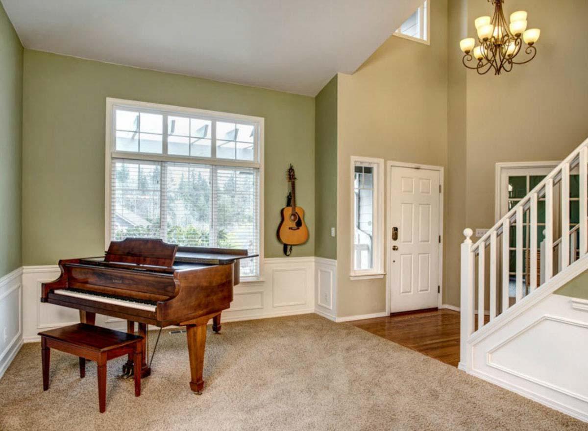 Interior view of a spacious entryway with a grand piano, large window, double door, and staircase.