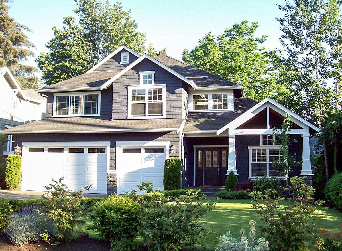 Two-story house plan exterior with double garage, gabled dormers, shingle siding, and covered entry with decorative gable.