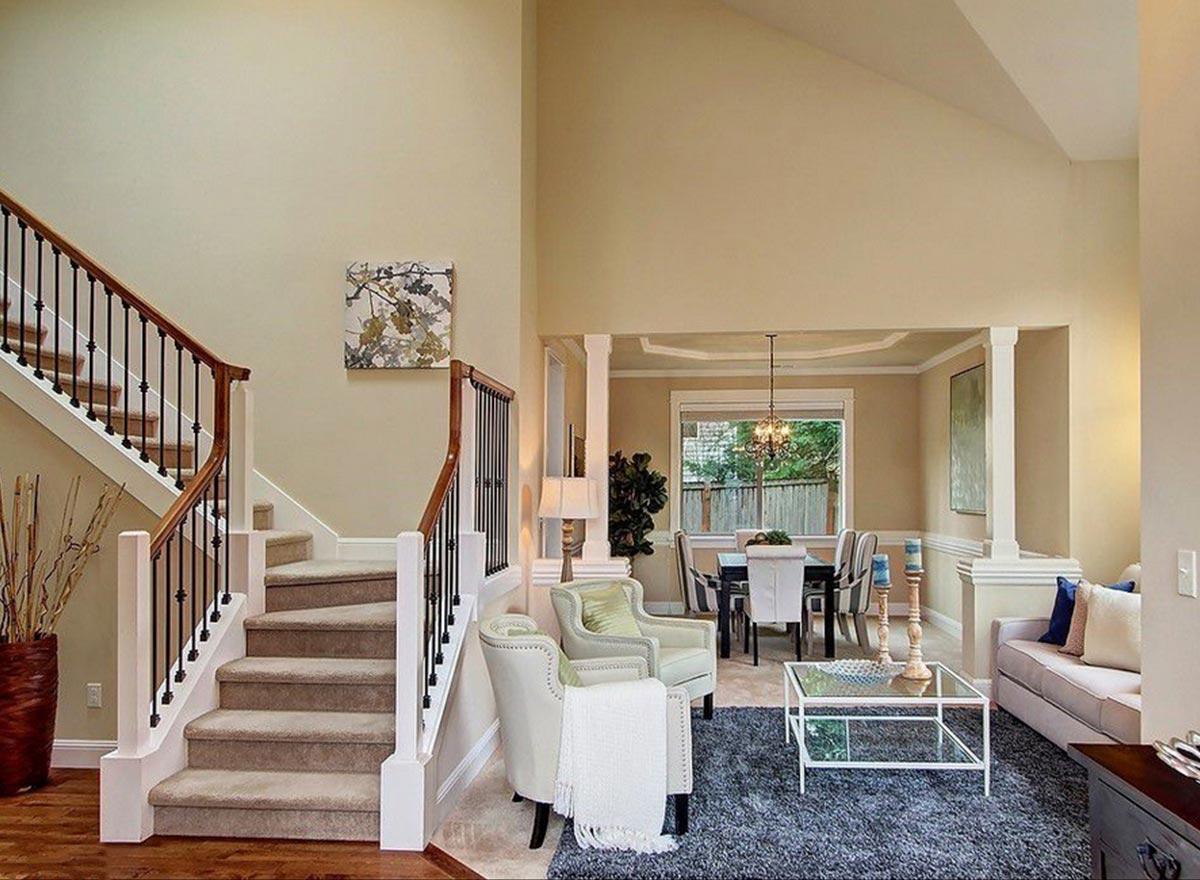 Interior view of a house with a grand staircase, open dining area, and living space with vaulted ceilings.