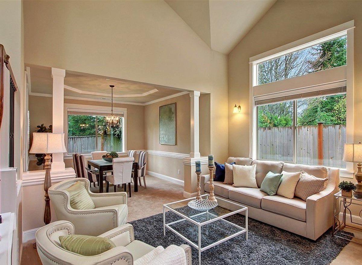 Great room with vaulted ceiling, fireplace, and large windows opening to dining area with coffered ceiling.