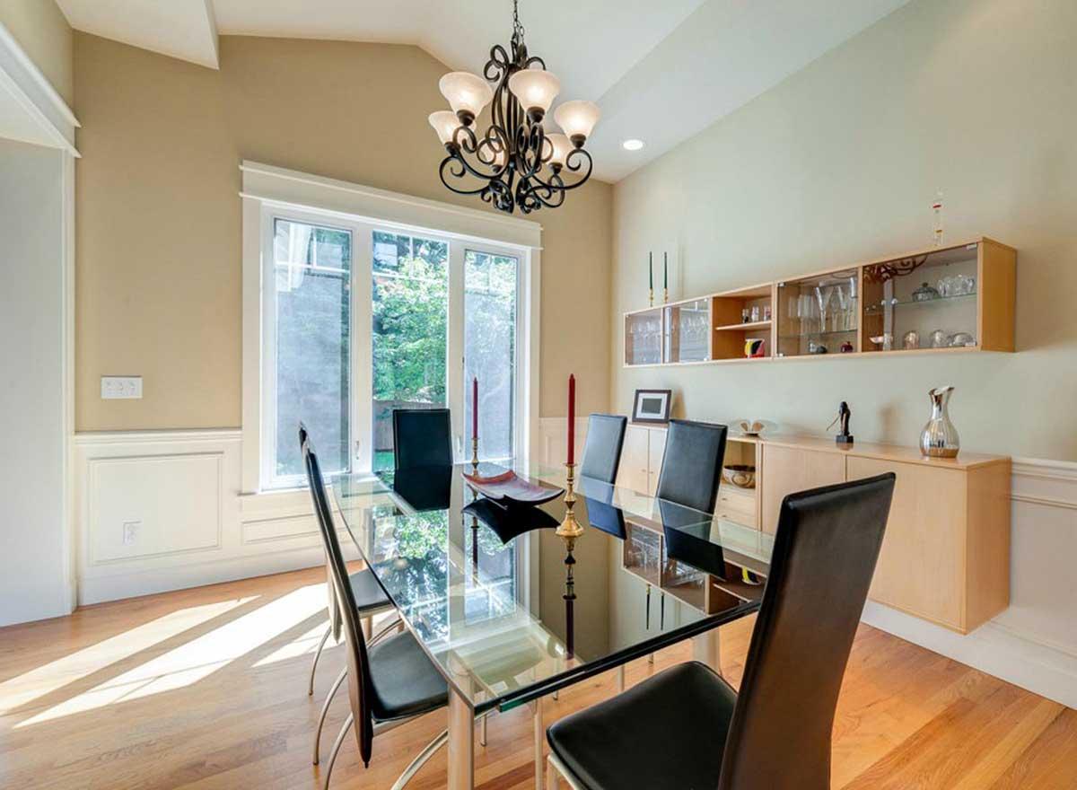 Dining room with glass tabletop, six chairs, vaulted ceiling, buffet, and wall-mounted display cabinets.