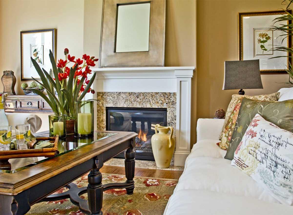 Living room featuring a fireplace with granite surround, a wooden coffee table with mirrored top, and a white sofa with decorative pillows.