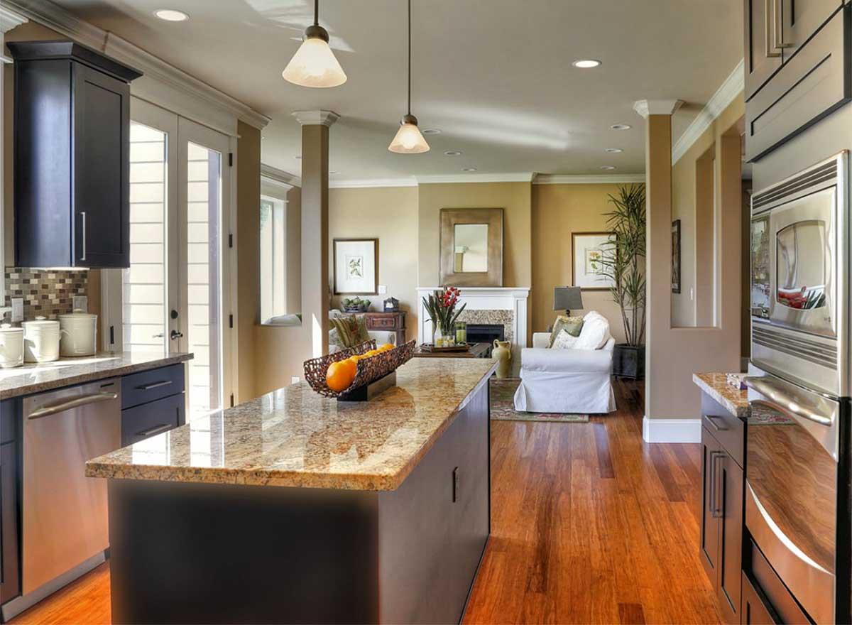 Open concept kitchen and living area with large island, fireplace, and white sofa.