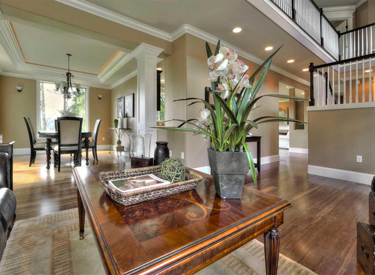 Interior view of a living area with coffered ceiling, dining room access, and a staircase to the second floor.