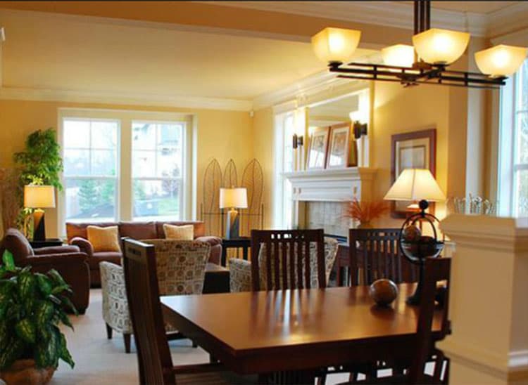 Interior view of a living and dining area with a fireplace, large windows, and furniture.