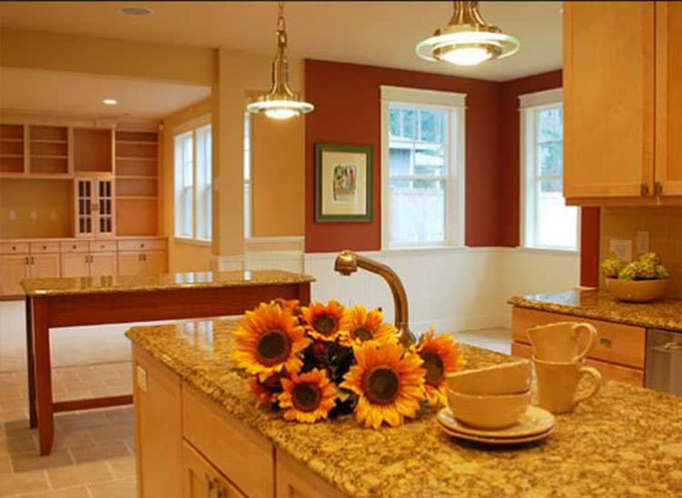 Interior kitchen view with granite countertops, island, built-in cabinets, and pendant lighting.