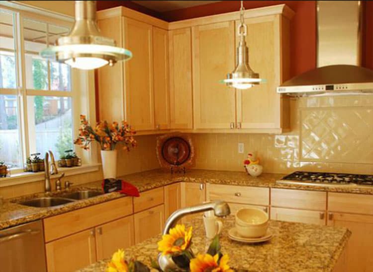 Kitchen with light wood cabinets, granite countertops, double sink, and stainless steel range hood.